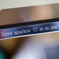 Gravering van een hartje tussen de gegraveerde tekst op een zilveren fotolijst