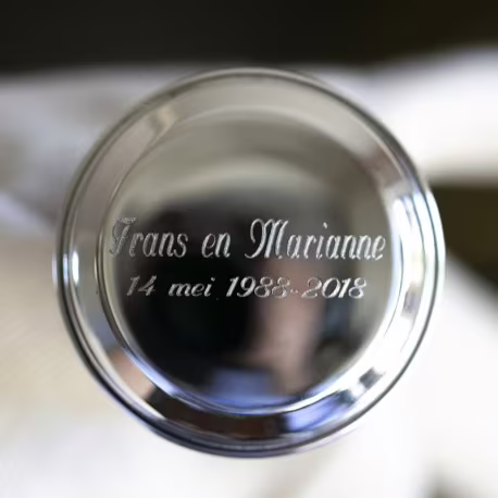 Gravering van twee namen met de trouwdatum eronder gecentreerd op een zilveren kurk