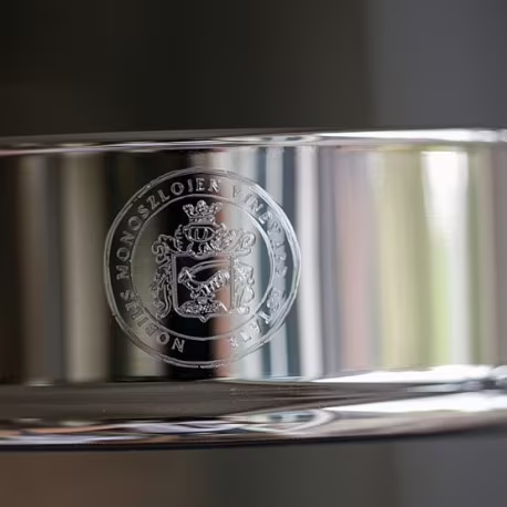 graveervoorbeeld van een familiewapen op een zilveren flessenbak