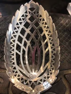 Met de hand uitgezaagd patroon in een zilveren natfruitlepel.