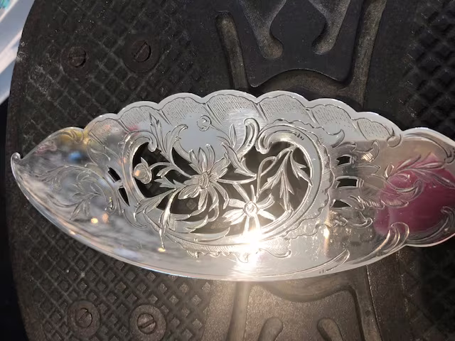 Een zilveren visdienschep, uitgezaagd, gegraveerd en gematteerd.